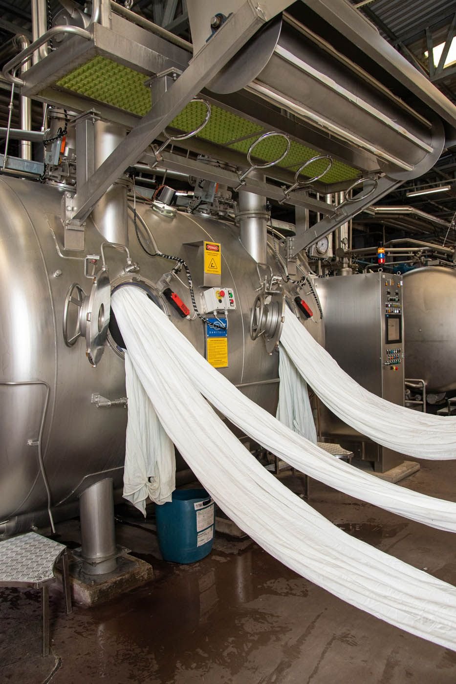 Equipamento de tingimento com malha branca saindo da máquina